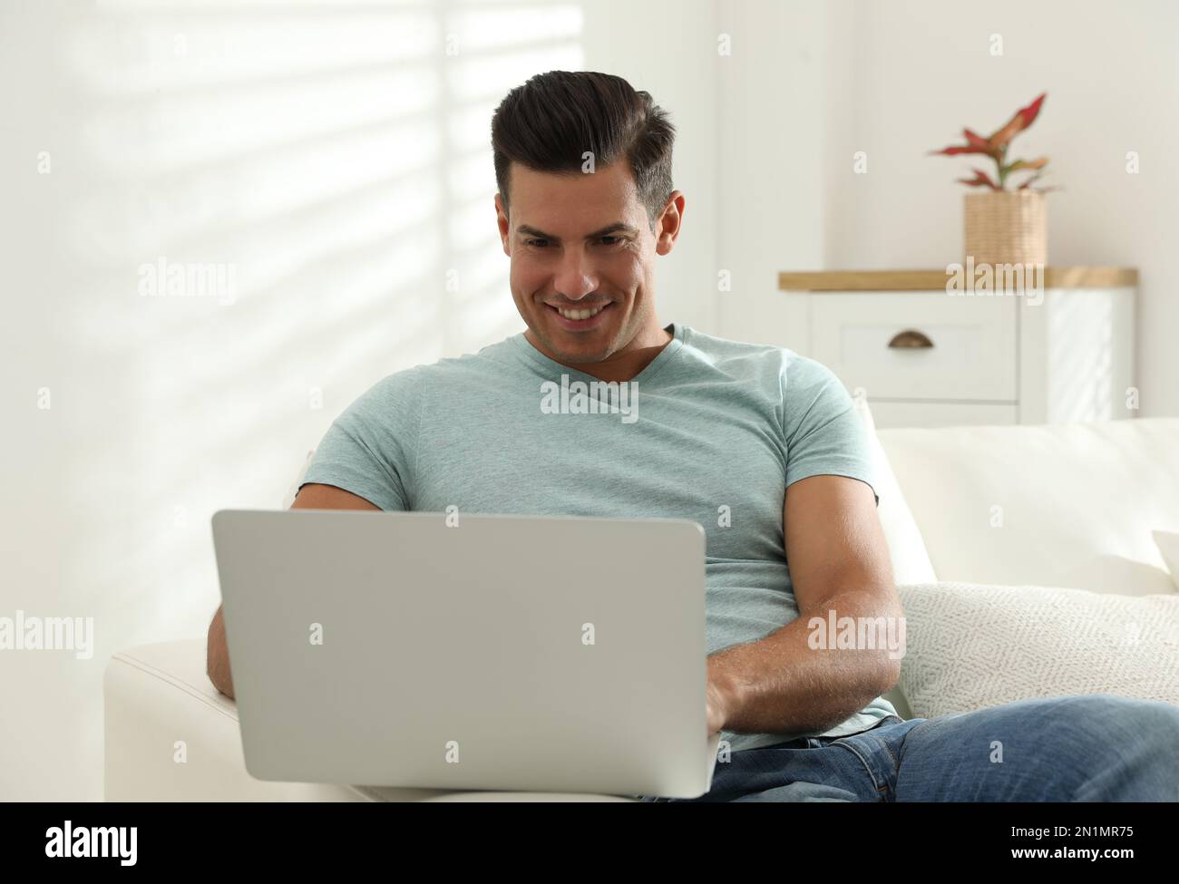 Man using laptop for search on sofa at home Stock Photo