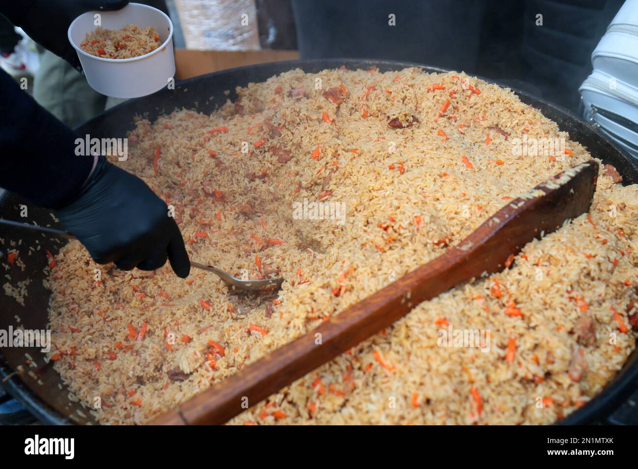 LVIV, UKRAINE - FEBRUARY 01, 2023 - Guests of the event are treated to traditional Kazakh pilaf during the opening of the fourth Yurt of Invincibility in Ukraine, a large tent where residents can eat and warm up, Lviv, capital of Ukraine. Stock Photo