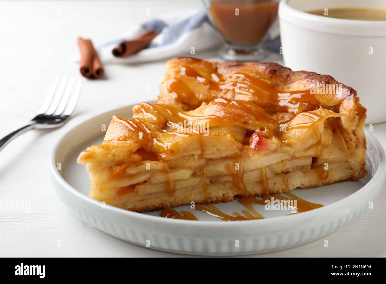 Slice of traditional apple pie on white wooden table, closeup Stock Photo