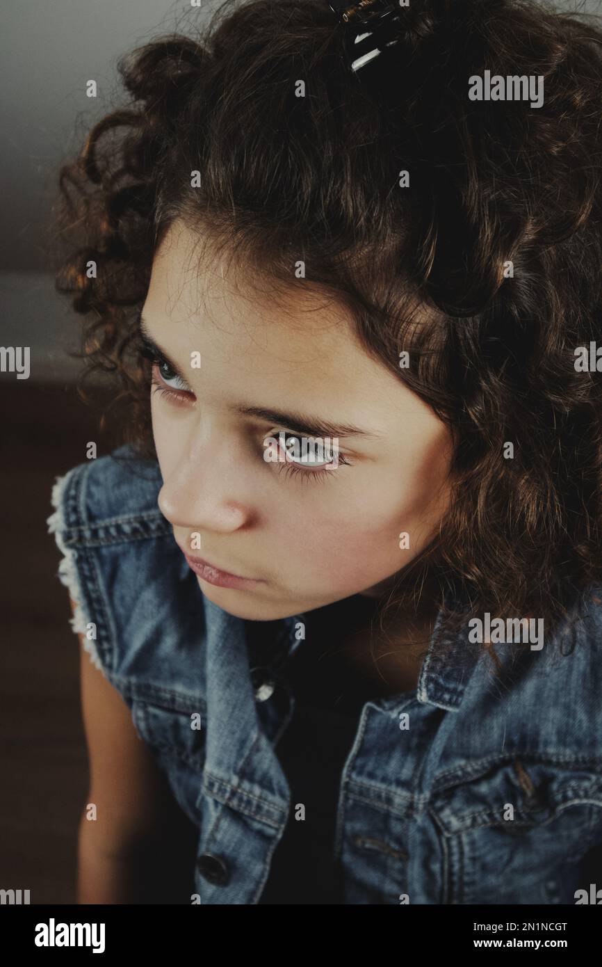 A young girl with  in a denim vest looks up Stock Photo