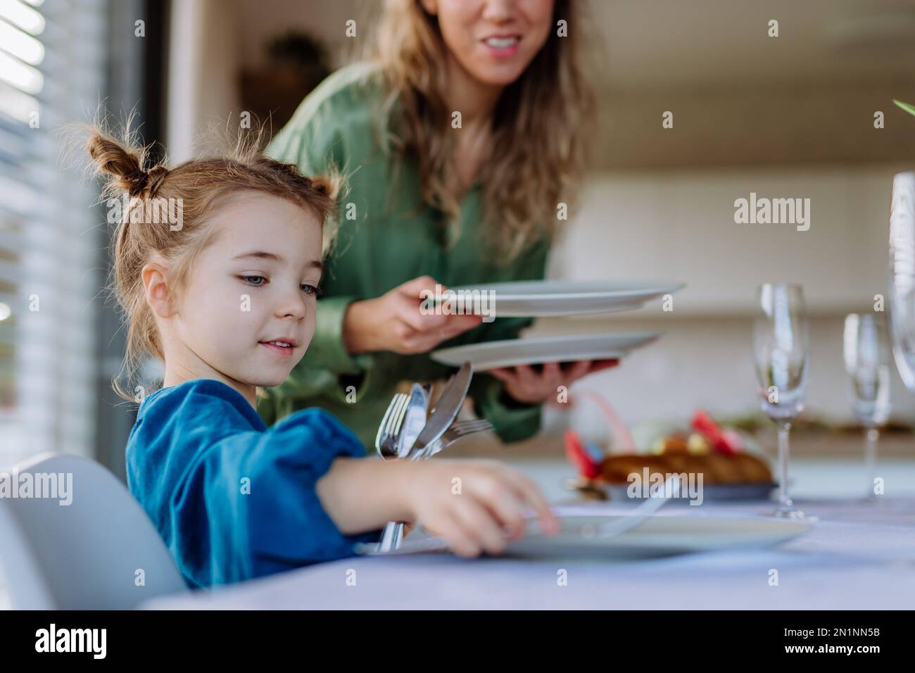 Close-up of mother with her daughter setting table, celebrating Easter. Stock Photo