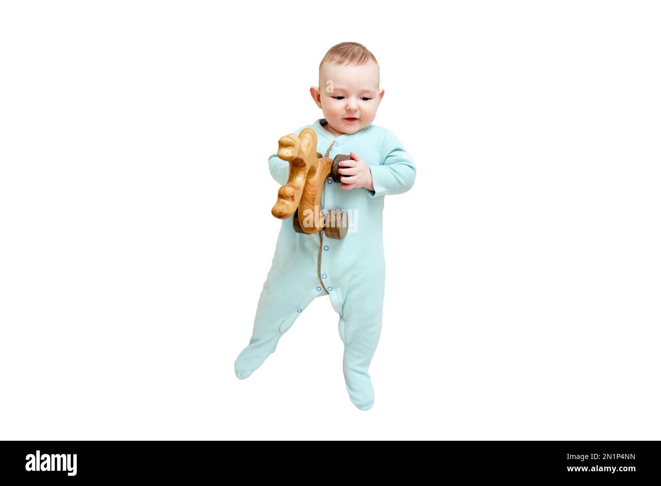 Happy baby lies in mint color clothes with wooden toys, isolated on a white background. Smiling child in turquoise pajamas, top view. Kid aged six mon Stock Photo