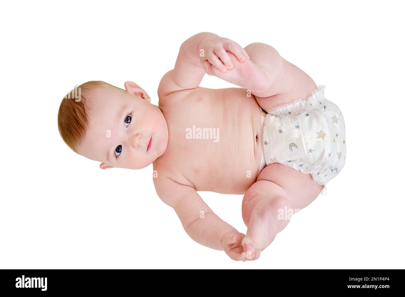 A happy infant baby with teething teeth in a diaper pulls his hand into his mouth, isolated on a white background. Funny child in a crib. Kid aged six Stock Photo