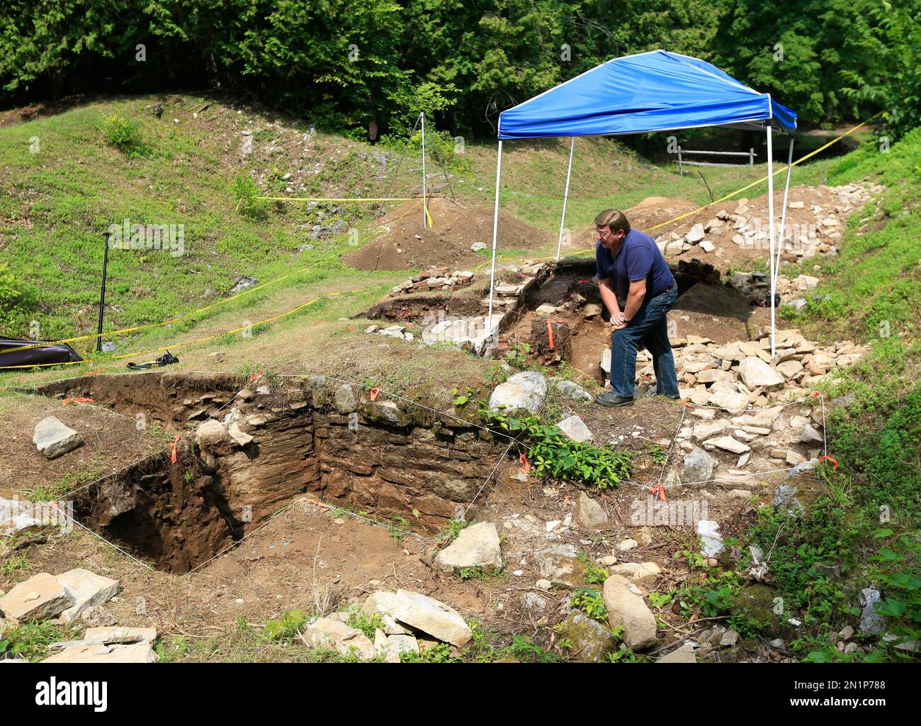Archaeologist David Starbuck poses near stone walls unearthed at Lake