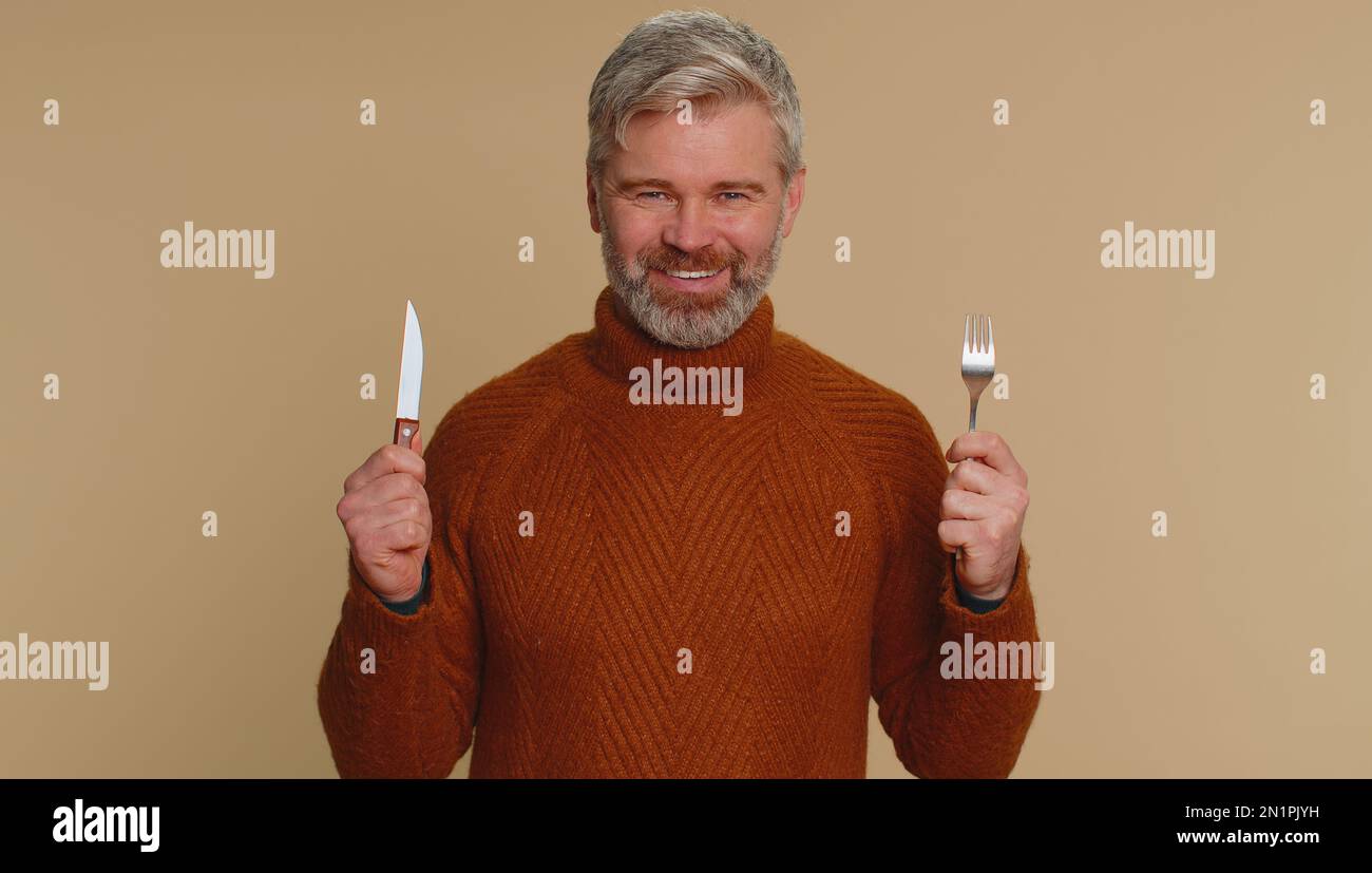 Ready to eat. Hungry middleaged man with fork, knife waiting for