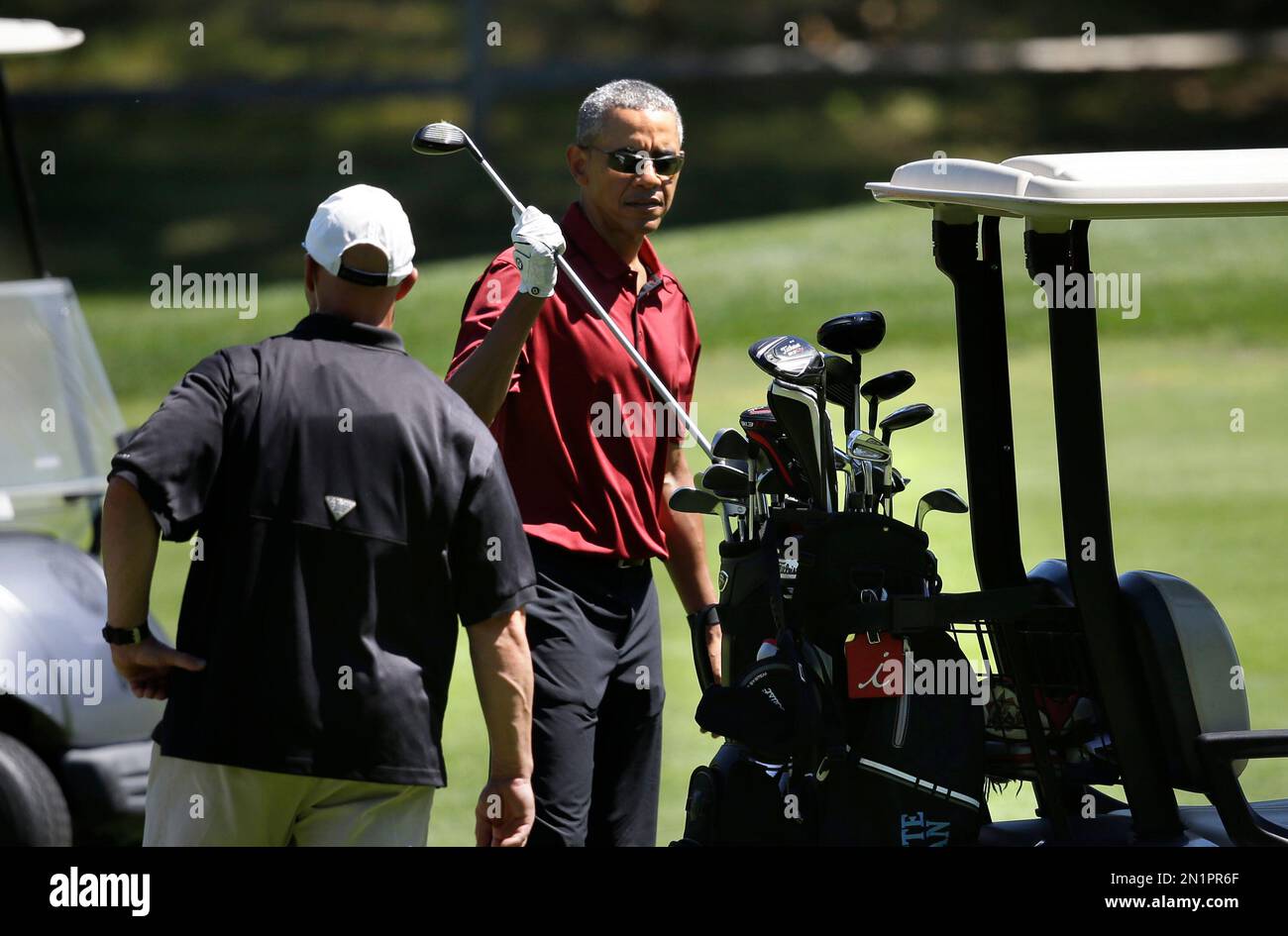 President Barack Obama returns a club to the cart while golfing Friday, Aug. 14, 2015, at Farm Neck Golf Club, in Oak Bluffs, Mass., on the island of Martha's Vineyard. The president, first lady Michelle Obama, and daughter Sasha are vacationing on the island. (AP Photo/Steven Senne) Stock Photo