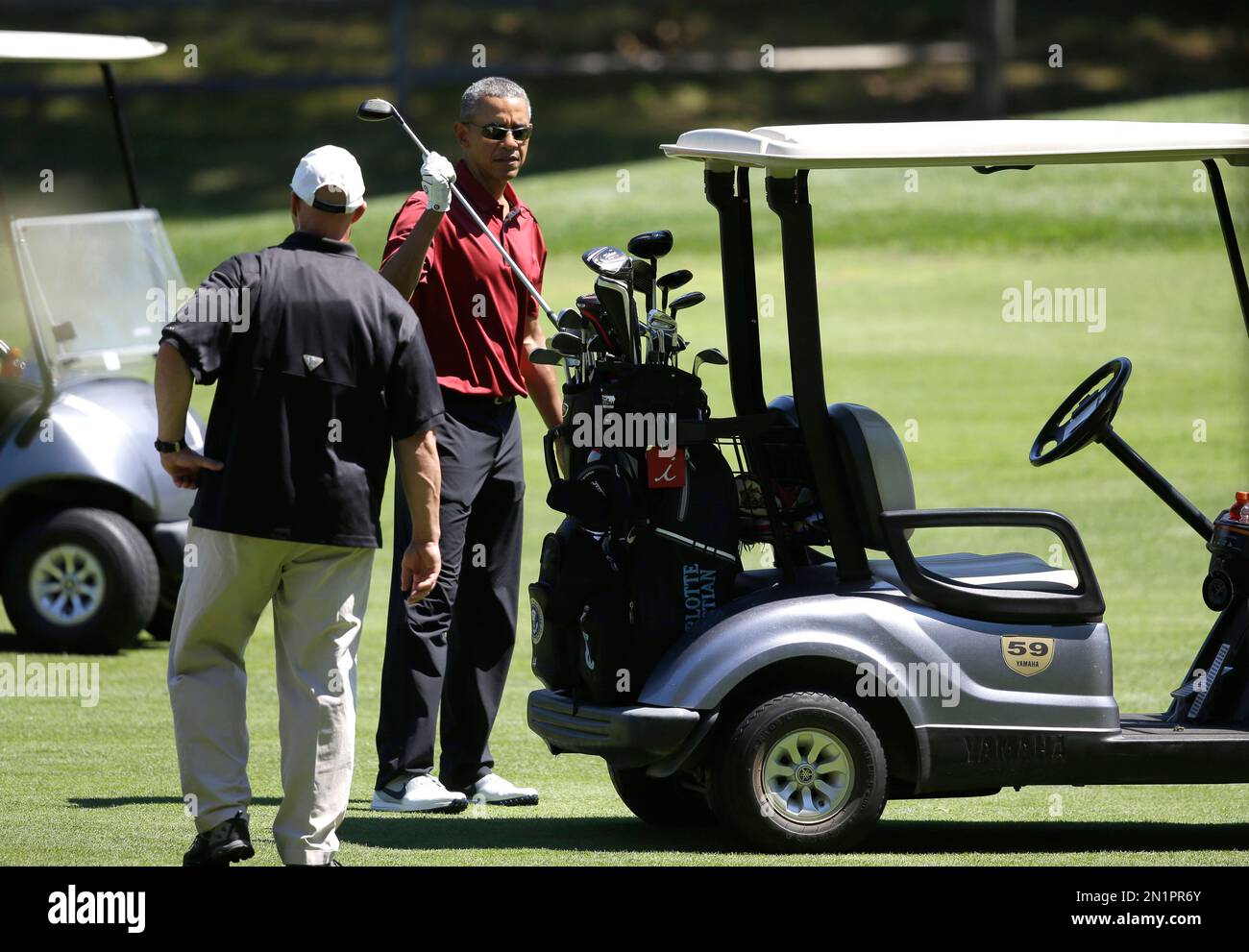 President Barack Obama returns a club to the cart while golfing Friday, Aug. 14, 2015, at Farm Neck Golf Club, in Oak Bluffs, Mass., on the island of Martha's Vineyard. The president, first lady Michelle Obama, and daughter Sasha are vacationing on the island. (AP Photo/Steven Senne) Stock Photo