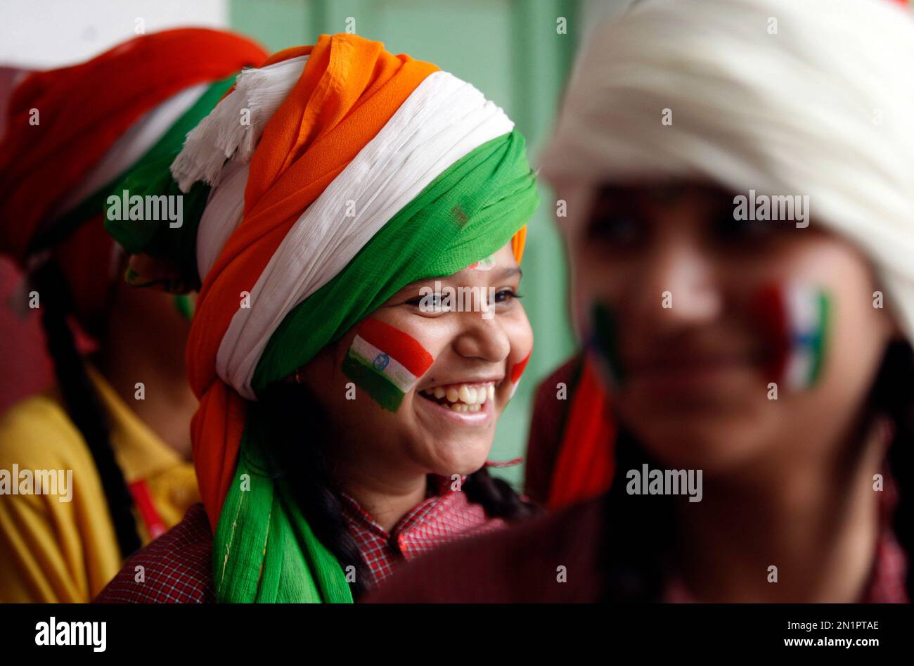 A girl, with her face painted in tricolor Indian flag, smiles as she ...