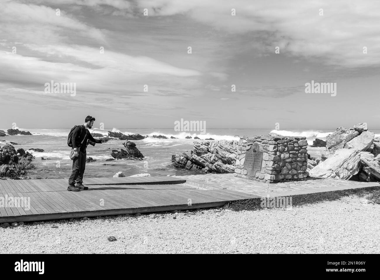 Agulhas National Park, South Africa - Sep 22, 2022: Tourist taking photos with cellphone of the plaque at Cape L'Agulhas, the southern-most tip of Afr Stock Photo