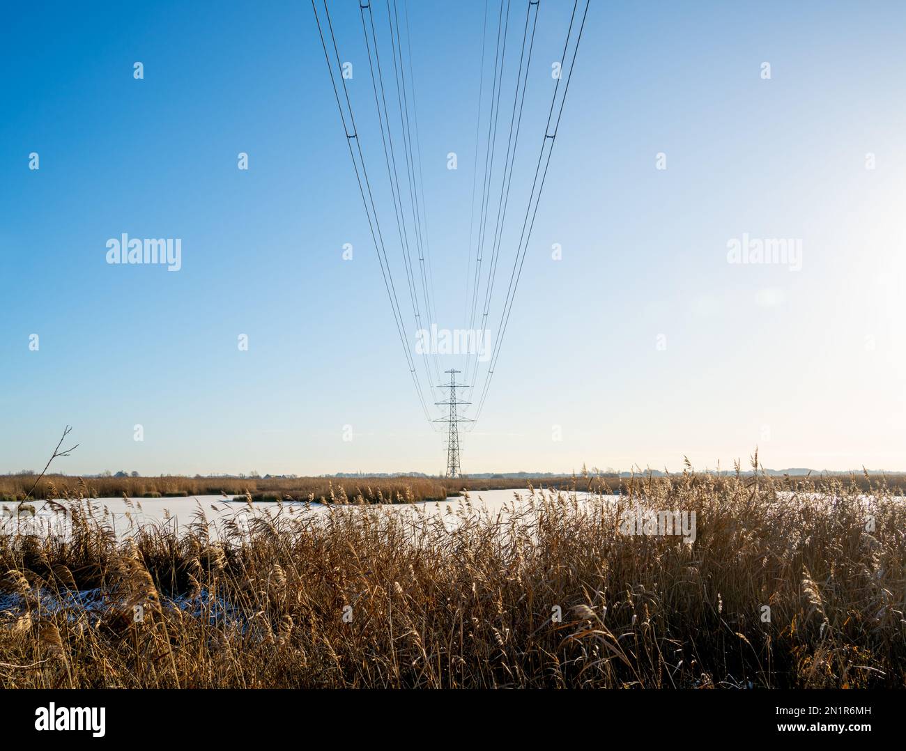 Winter landscape with frozen lake and row of power pylons Stock Photo ...