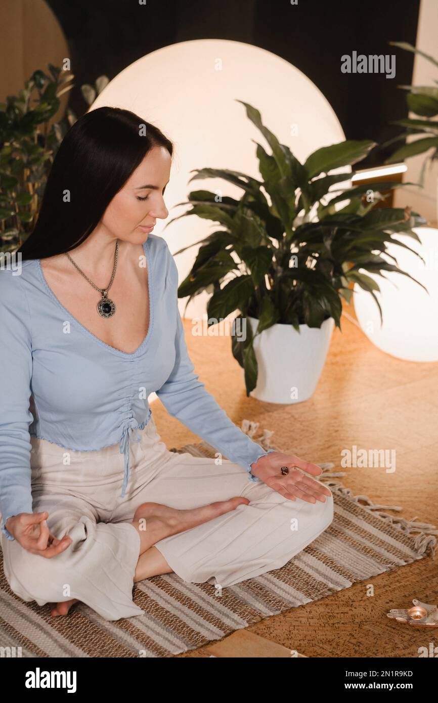 A young woman sitting in the Lotus position before the Game was playing and holding game cubes in her hand. Stock Photo