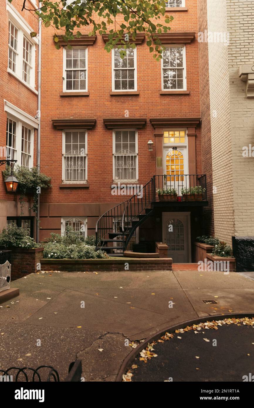 Urban street with fallen leaves on road and brick buildings in New York ...