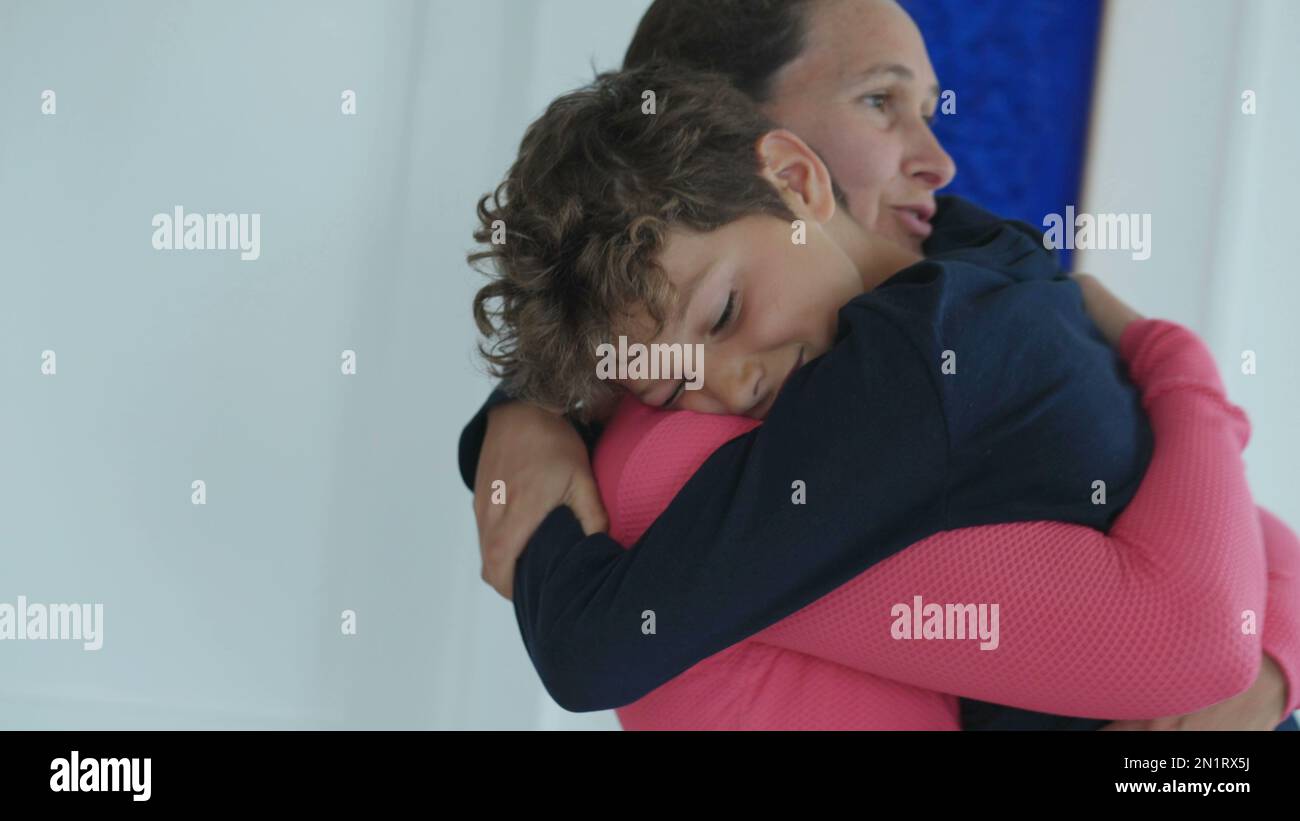 Candid mother embracing young boy. Mom holding kid in arms. Authentic