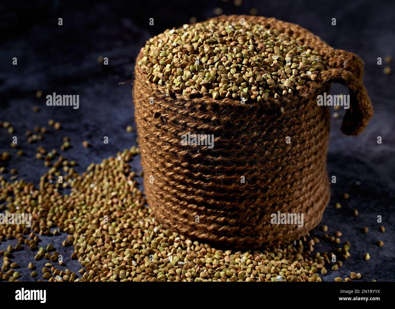 Green unprocessed buckwheat is in jute bag and scattered on the wooden table Stock Photo