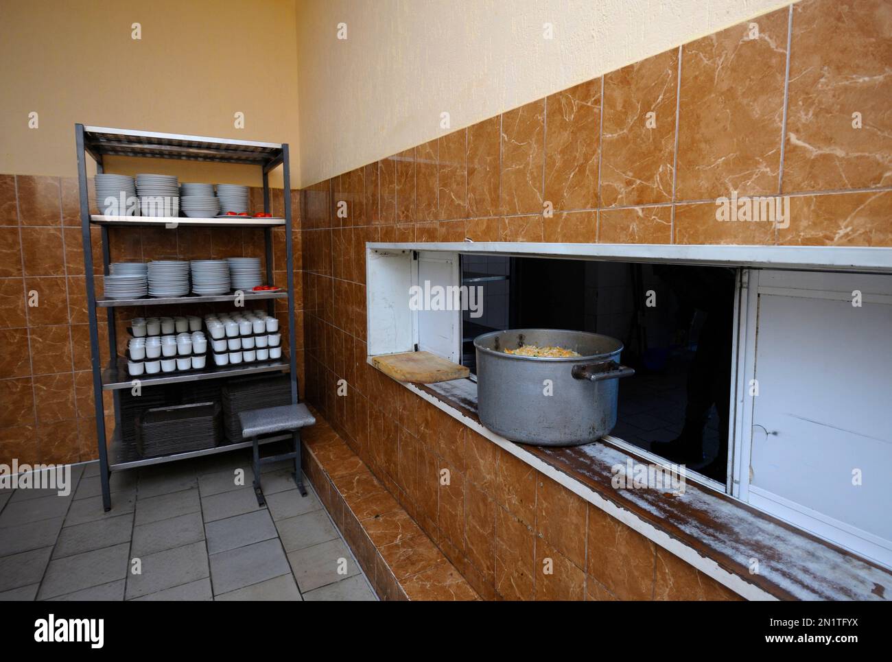 Pot with ready meal put on the window of serving bar, washed tableware put on shelves. Chow hall for soldiers, military base. Ukraine Stock Photo