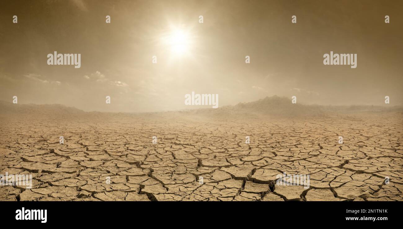 Barren terrain panorama, sun shining over cracked dried land and clouds of dust, climate change concept Stock Photo