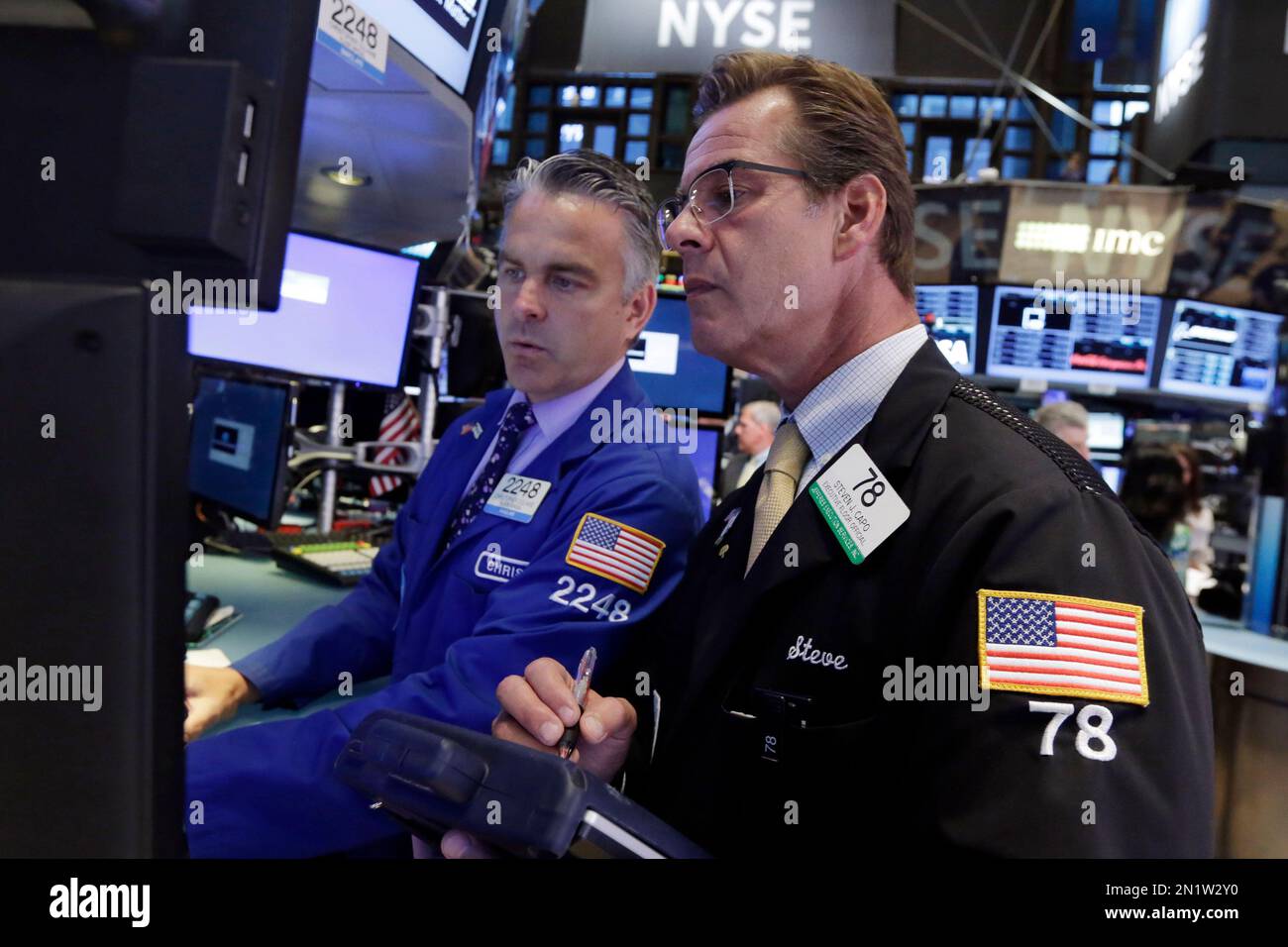 Specialist Christopher Culhane, left, and trader Steven Capo work on the floor of the New York Stock Exchange, Monday, Aug. 3, 2015. Stocks are opening slightly lower in the U.S. as energy companies slide along with the price of crude oil. (AP Photo/Richard Drew) Stock Photo