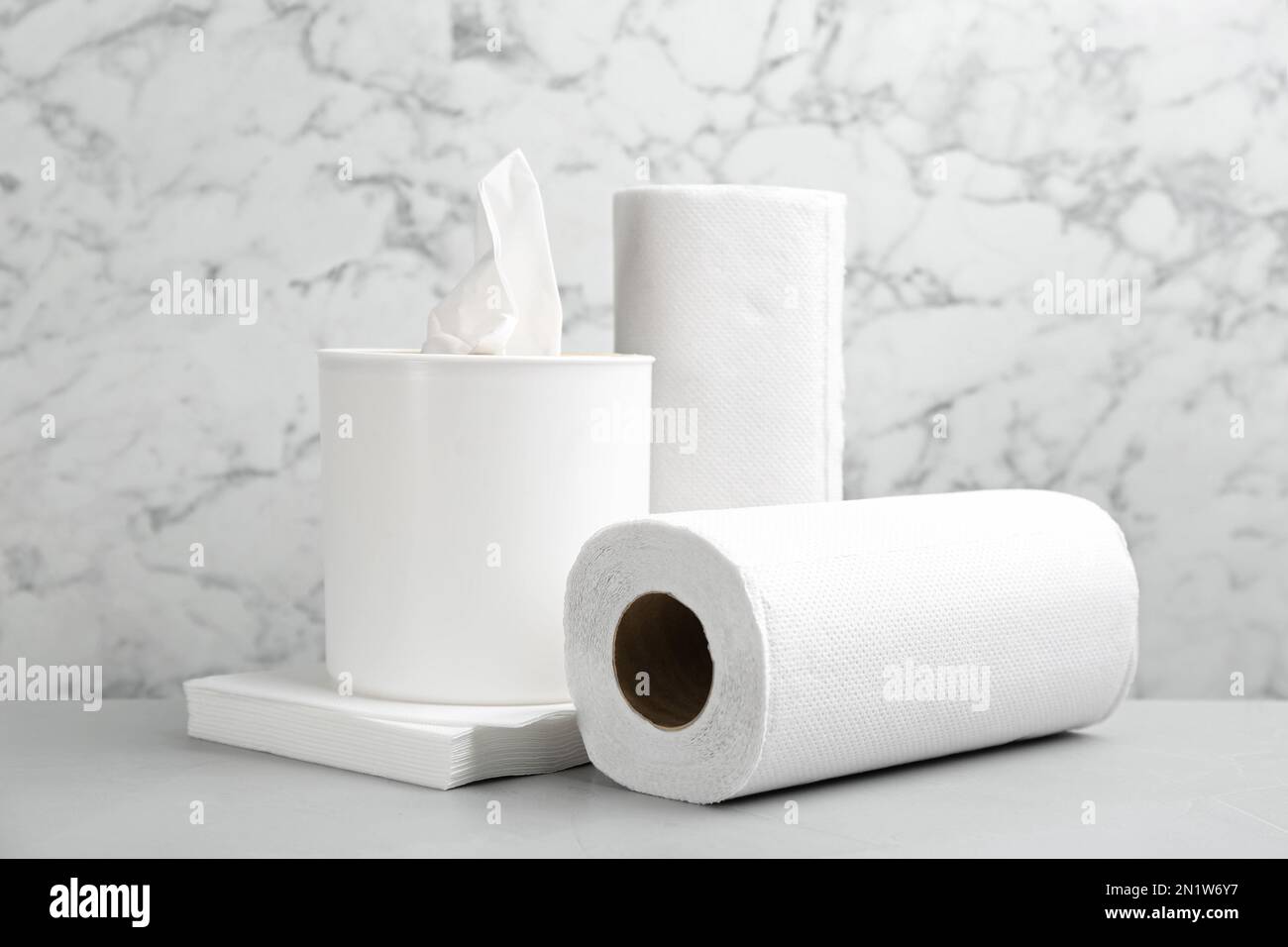 Clean napkins, box with tissues and rolls of paper towels on light table Stock Photo