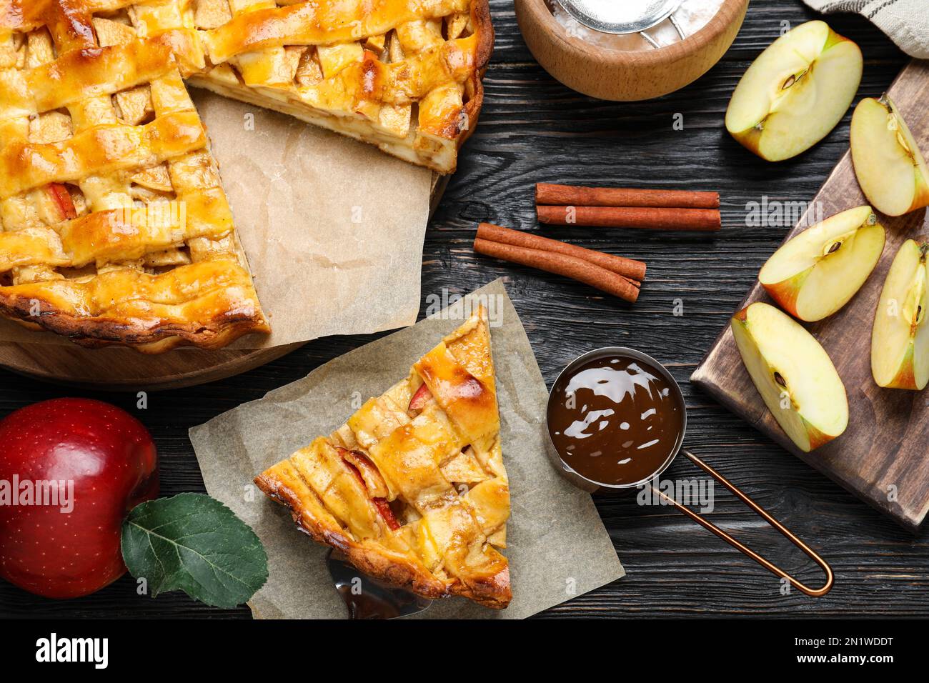 Traditional apple pie and ingredients on black wooden table, flat lay Stock Photo