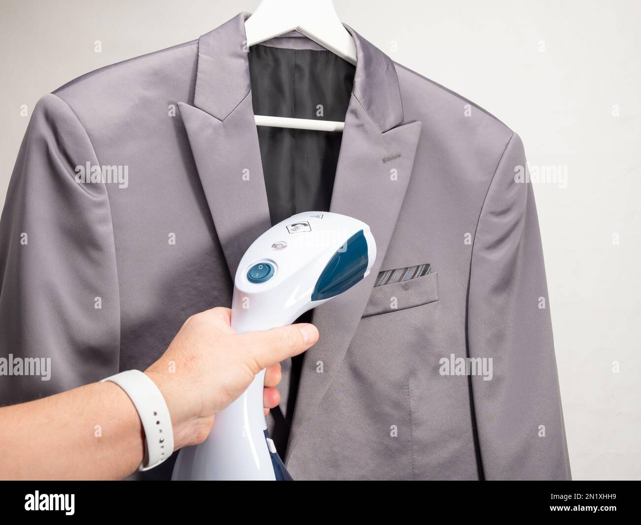In hand Steamer for clothes. The suit is ironed with a portable iron. Iron for ironing clothes