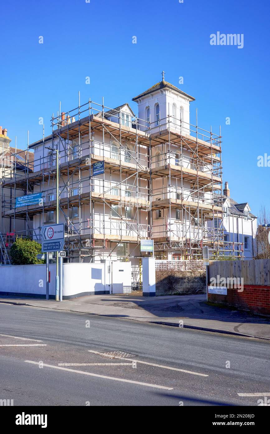 Behind Building Scaffolding surrounding a building with blue sky behind and road in ...
