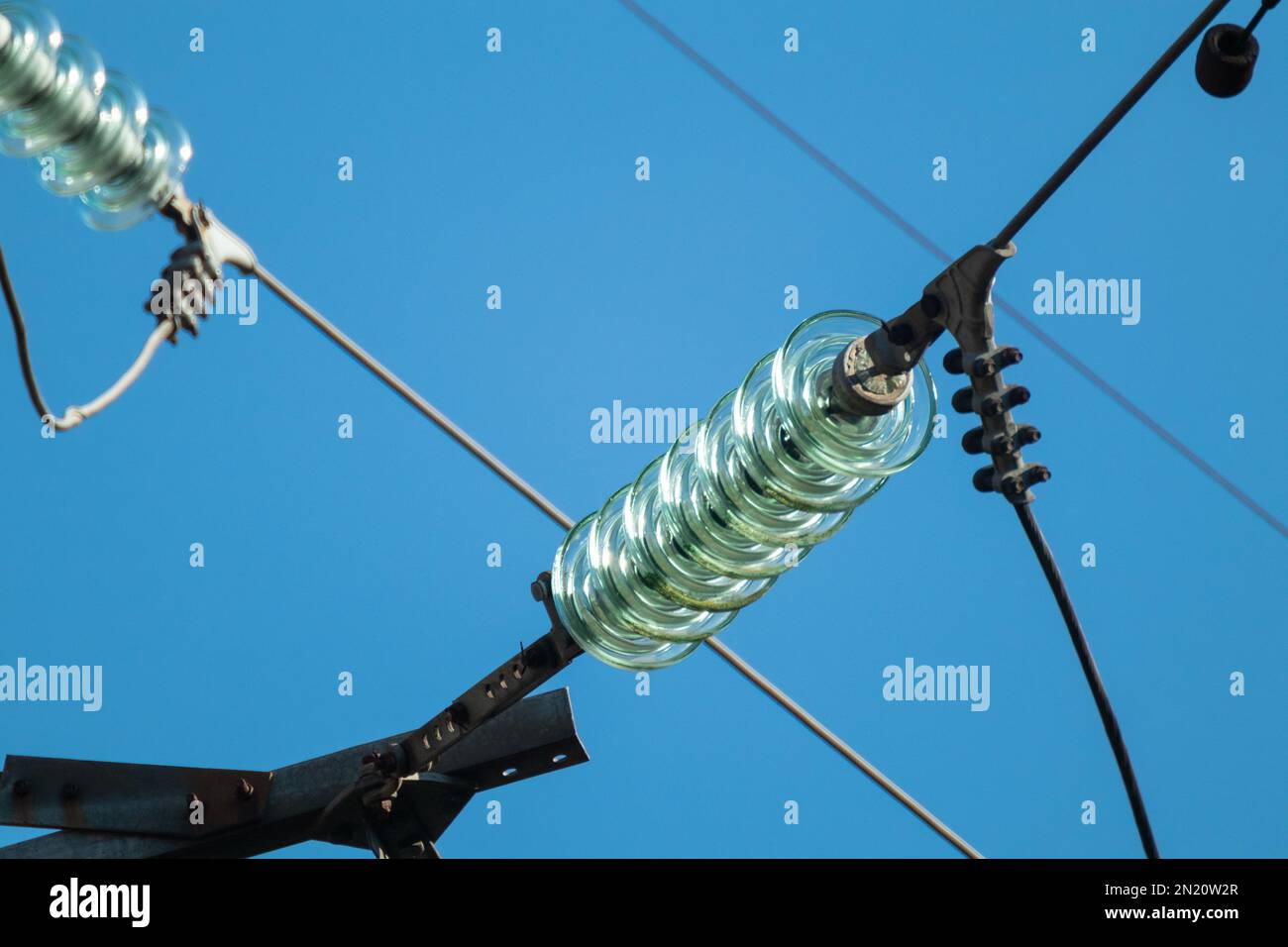 High voltage glass insulators closeup on electric transmission line with blue sky background