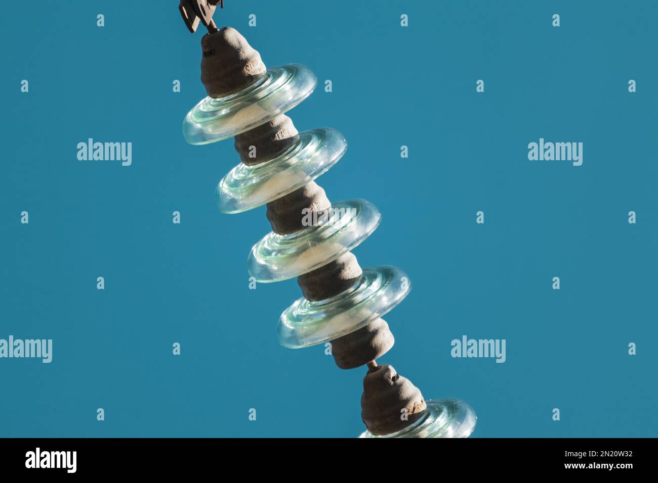 High voltage glass insulators electric line closeup details with blue sky background Stock