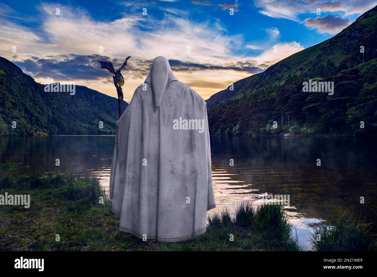 A legendary wise wizard wearing long white cloak and holding his magic staff looks across a mystical lake at sunset. 3D illustration and photo composi Stock Photo