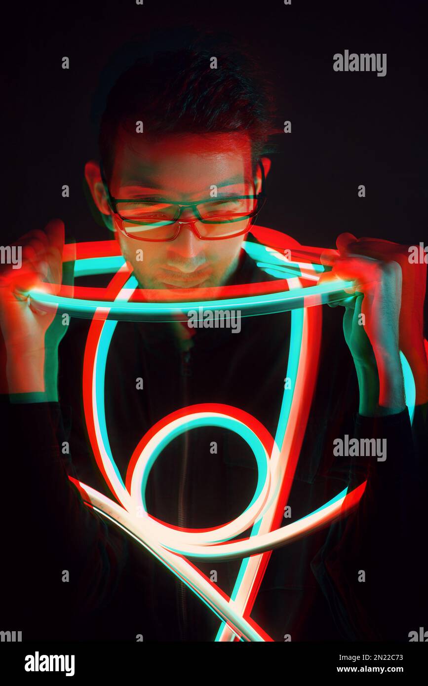 Glitch Double Exposure Futuristic Portrait in handsome young hipster man with trending glasses on wrapped with neon glow tape in neon light Stock Photo
