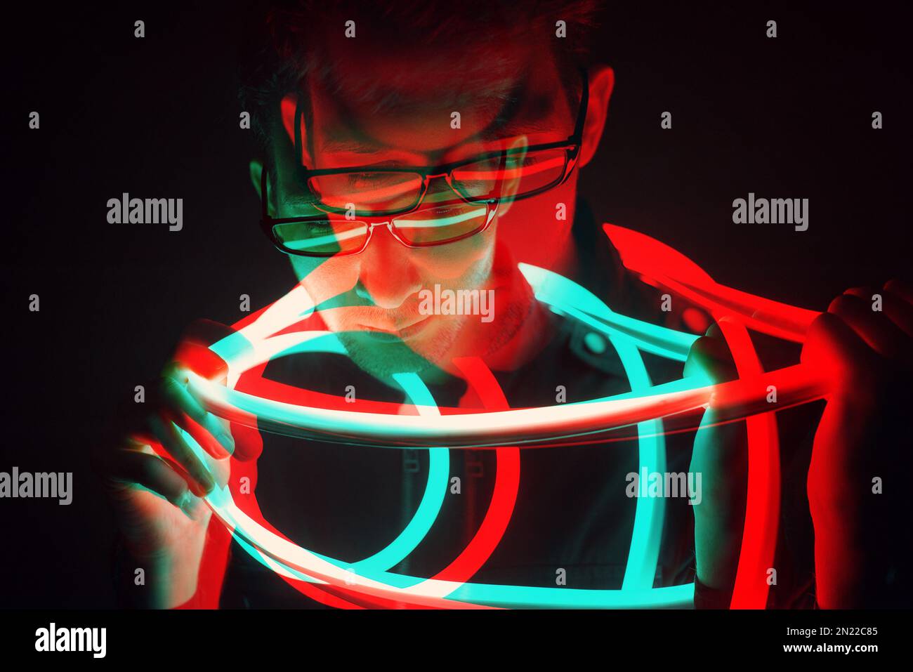 Glitch Double Exposure Futuristic Portrait in handsome young hipster man with trending glasses on wrapped with neon glow tape in neon light Stock Photo