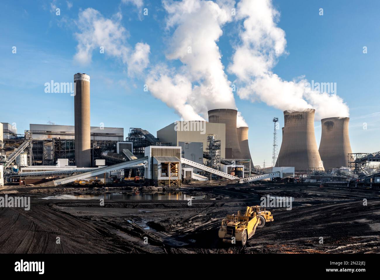 A heavy plant machine scraping coal from a fossil fuel stack at a large