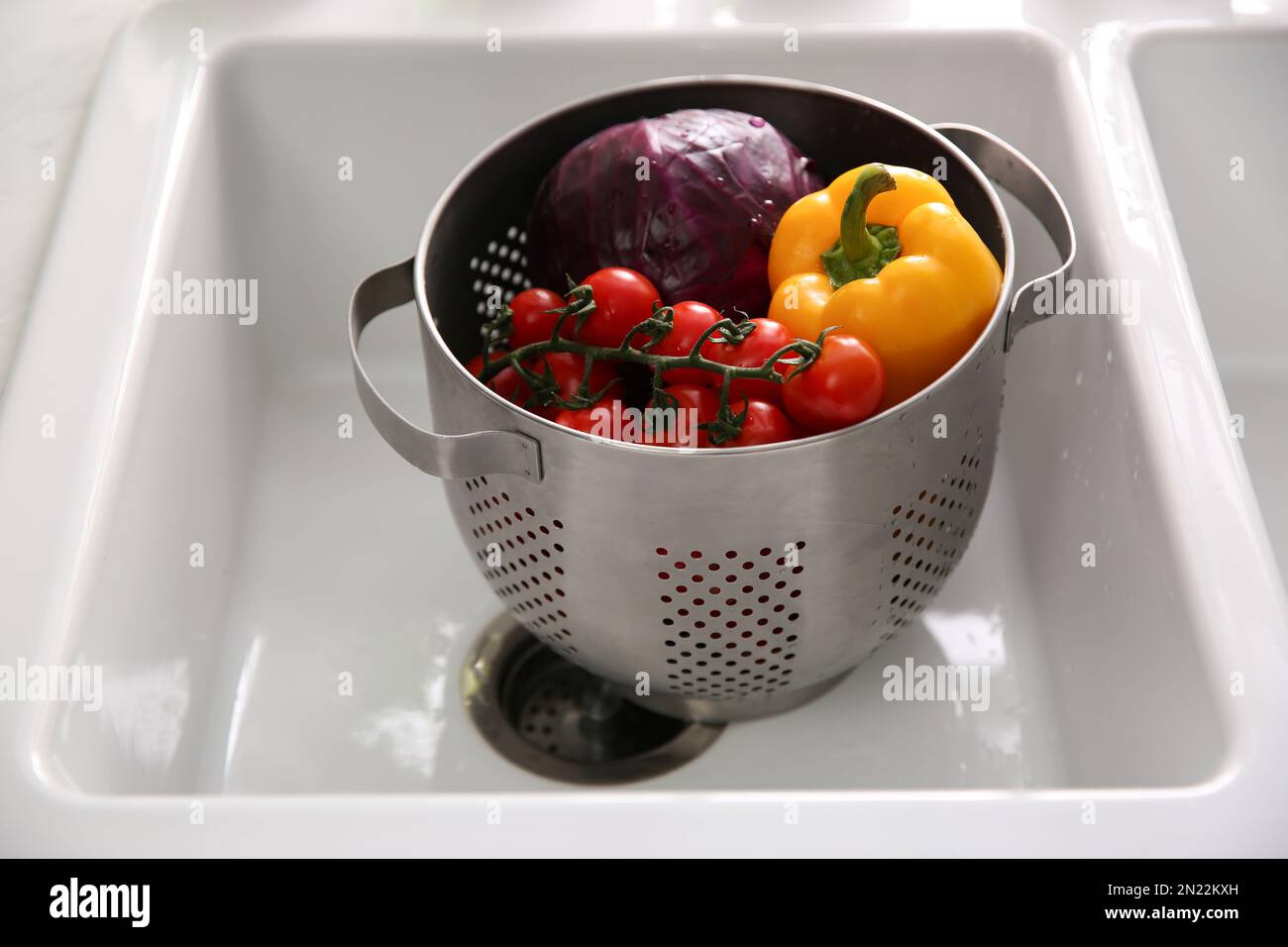 Colander pot with fresh vegetables in kitchen sink Stock Photo