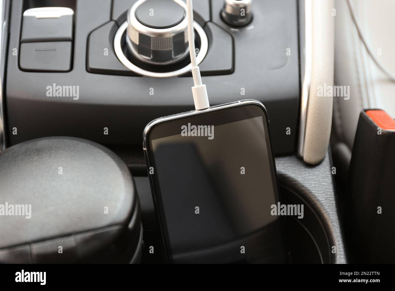 Mobile phone with charging cable in car, closeup Stock Photo