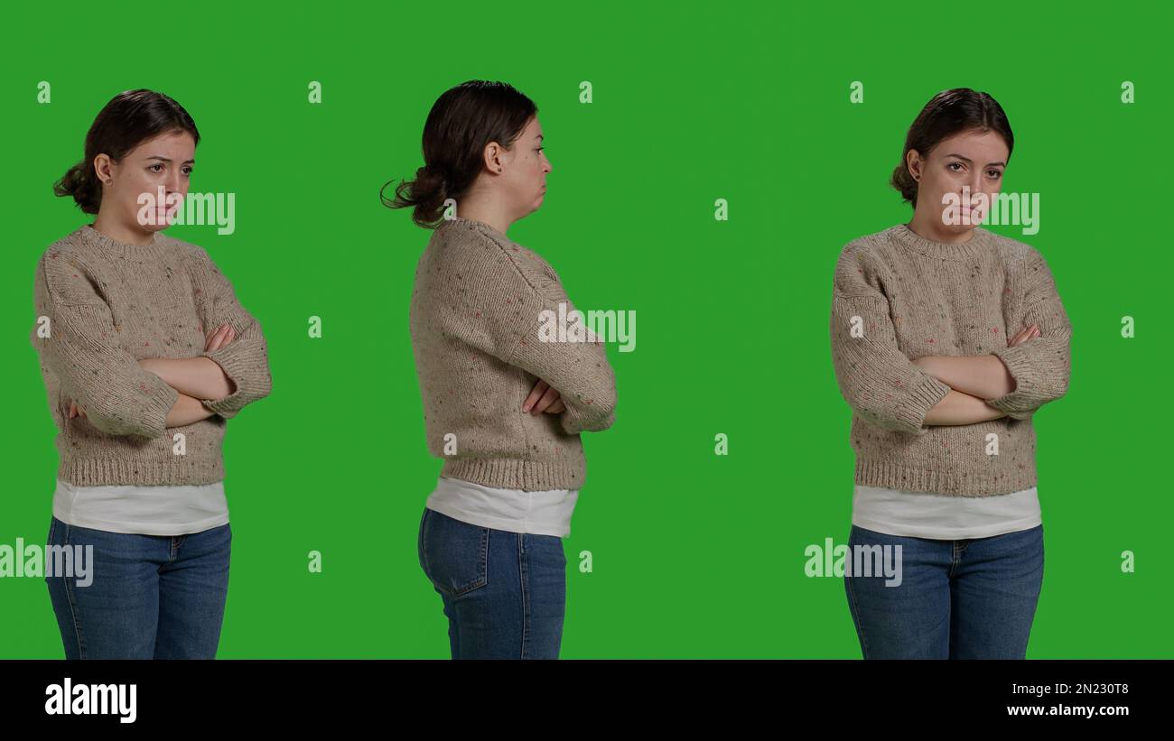 Depressed frustrated person acting sad and displeased, posing over green screen background, being disappointed and discouraged. Upset female model standing over full body studio backdrop. Stock Photo