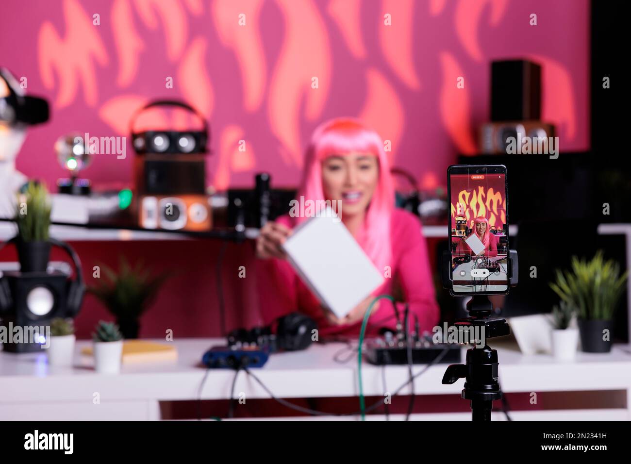 Asian woman with pink hair holding white box advertising product while ...