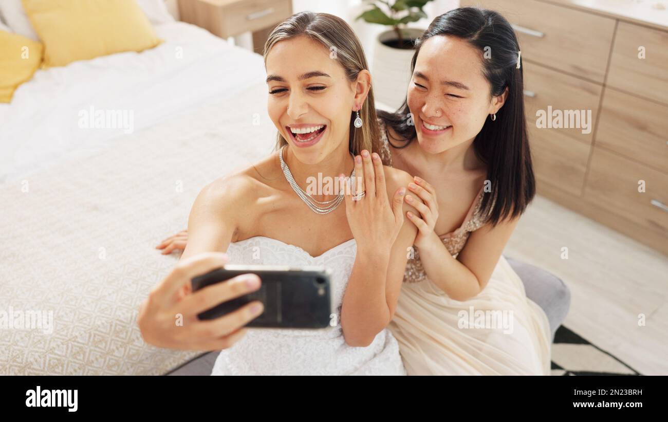 Bride, bridesmaid and selfie with phone, wedding and ring with a smile to post on social media. Happy woman and asian friend excited for marriage Stock Photo