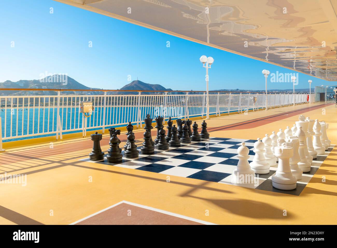 A large, giant size checker or chess board with black and white chess pieces set up on a deck of a large cruise ship at Cabo San Lucas, Mexico. Stock Photo