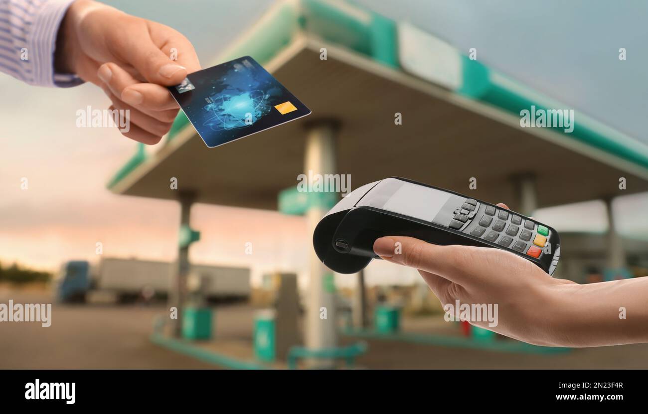 Woman paying for fuel using credit card via payment terminal at gas