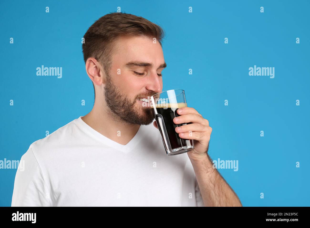 Handsome man with cold kvass on blue background. Traditional Russian summer drink Stock Photo