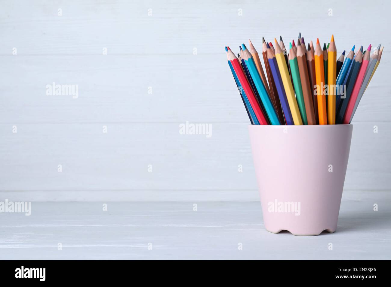 Colorful pencils in cup on white wooden table. Space for text Stock Photo