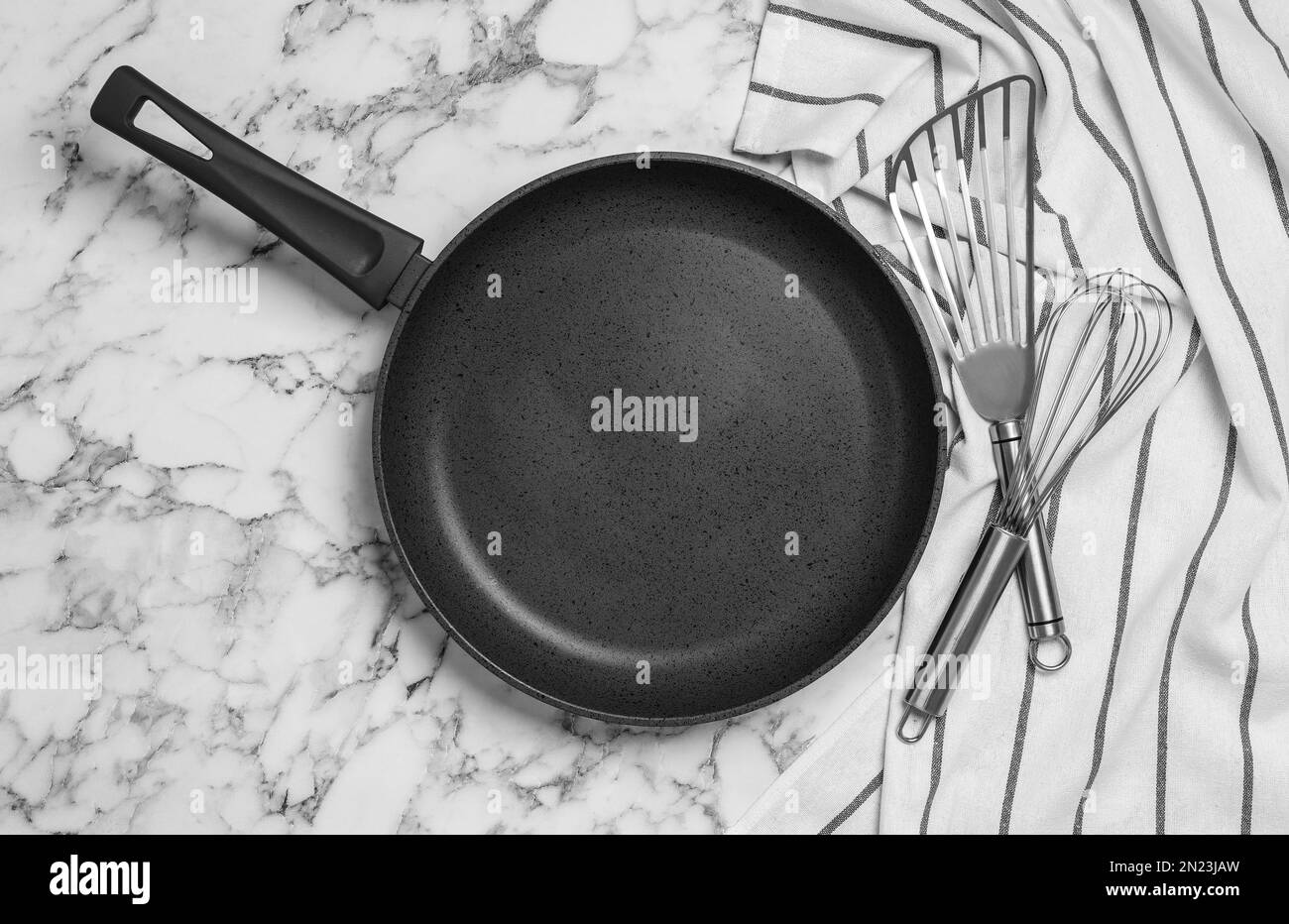 Frying pan, cooking utensils and tablecloth on white marble background, flat lay Stock Photo