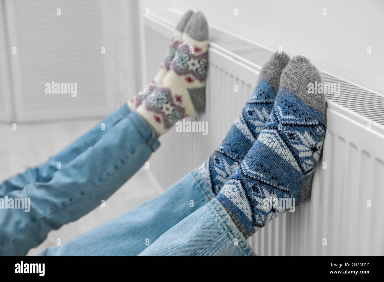 Couple warming legs on heating radiator near white wall, closeup Stock ...