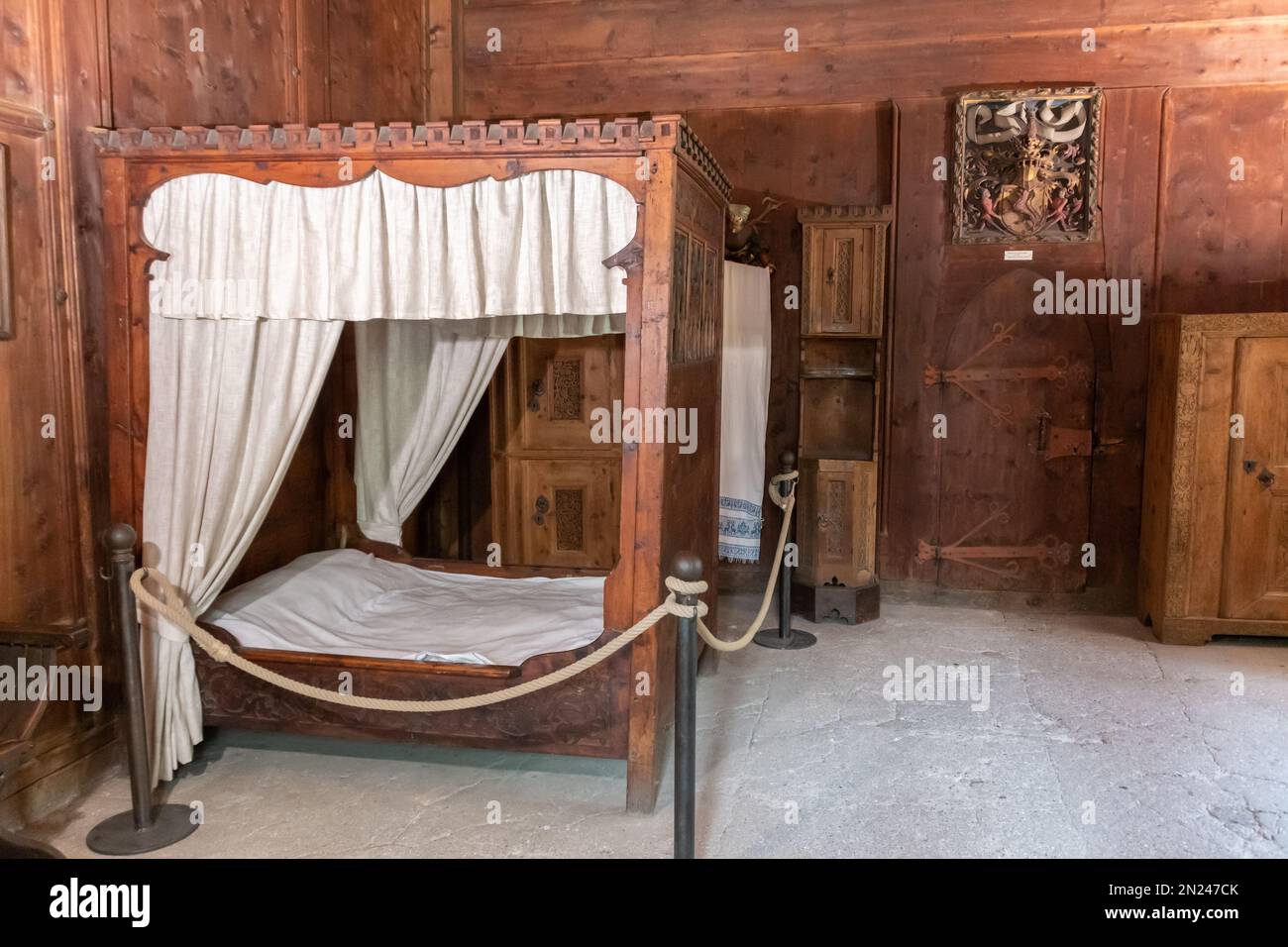 Bedroom with canopy bed of the princely castle (Castello Principesco or  Landesfurstlicheburg) with the statue of Saint George and a fresco of the cru Stock Photo