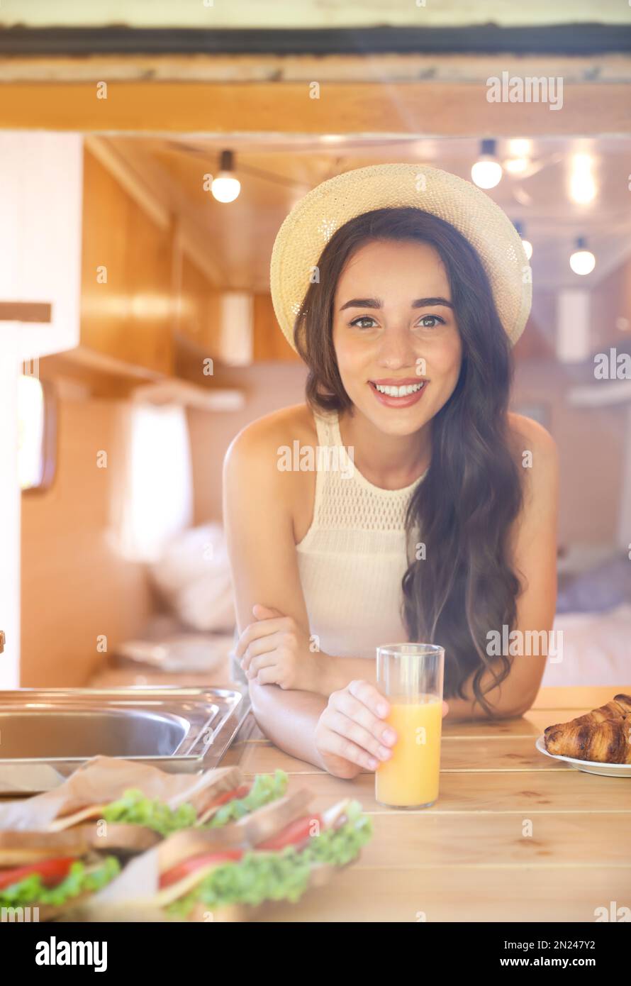 Young woman with glass of juice in trailer. Camping vacation Stock Photo