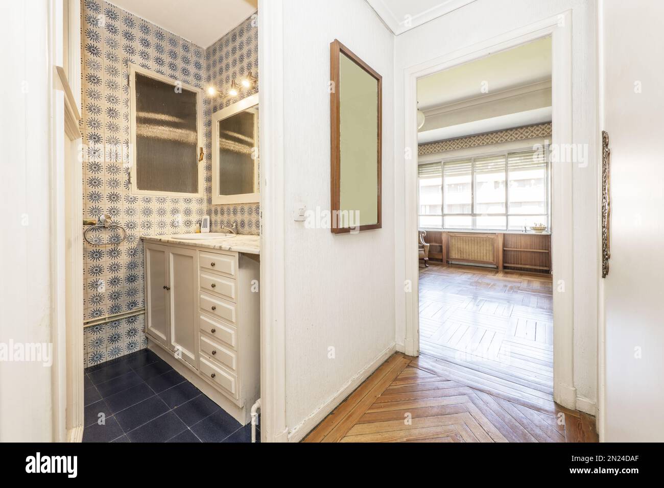 An en-suite toilet in a vintage home with nobel wooden flooring and white cabinets in the bathroom with lots of drawers Stock Photo