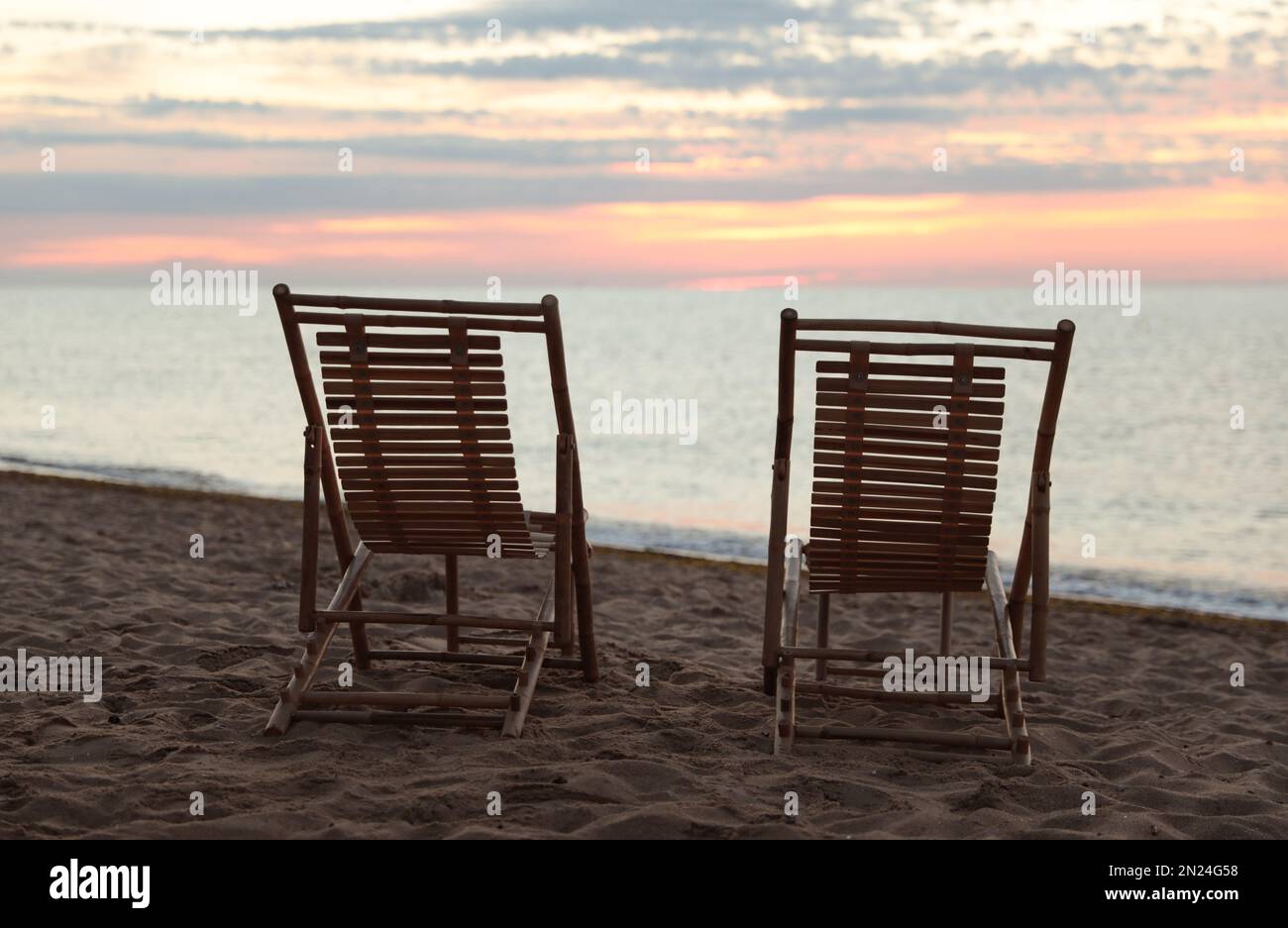 Wooden deck chairs on sandy beach at sunset. Summer vacation Stock ...