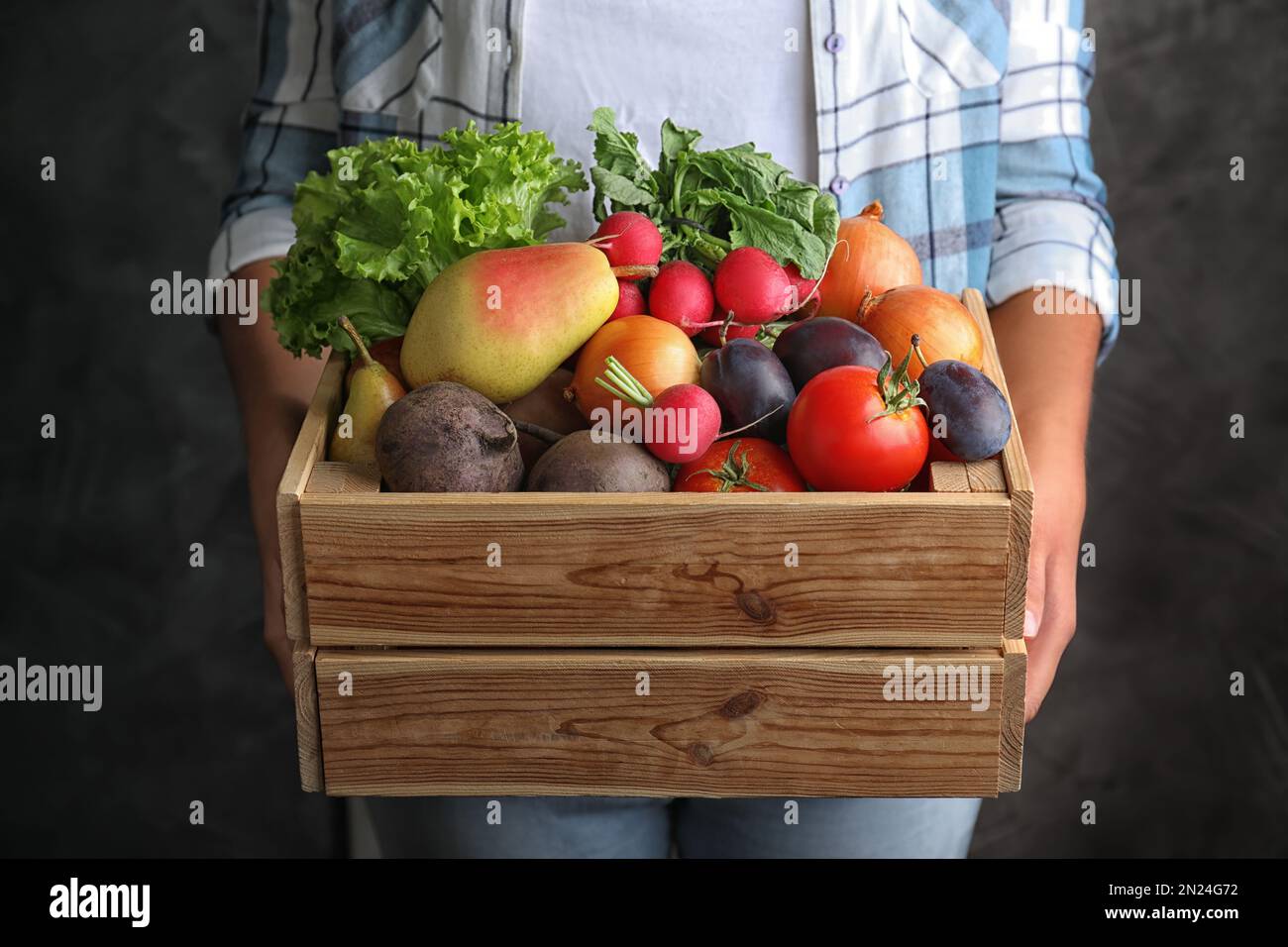Farmer holding wooden crate filled with fresh vegetables and fruits on ...