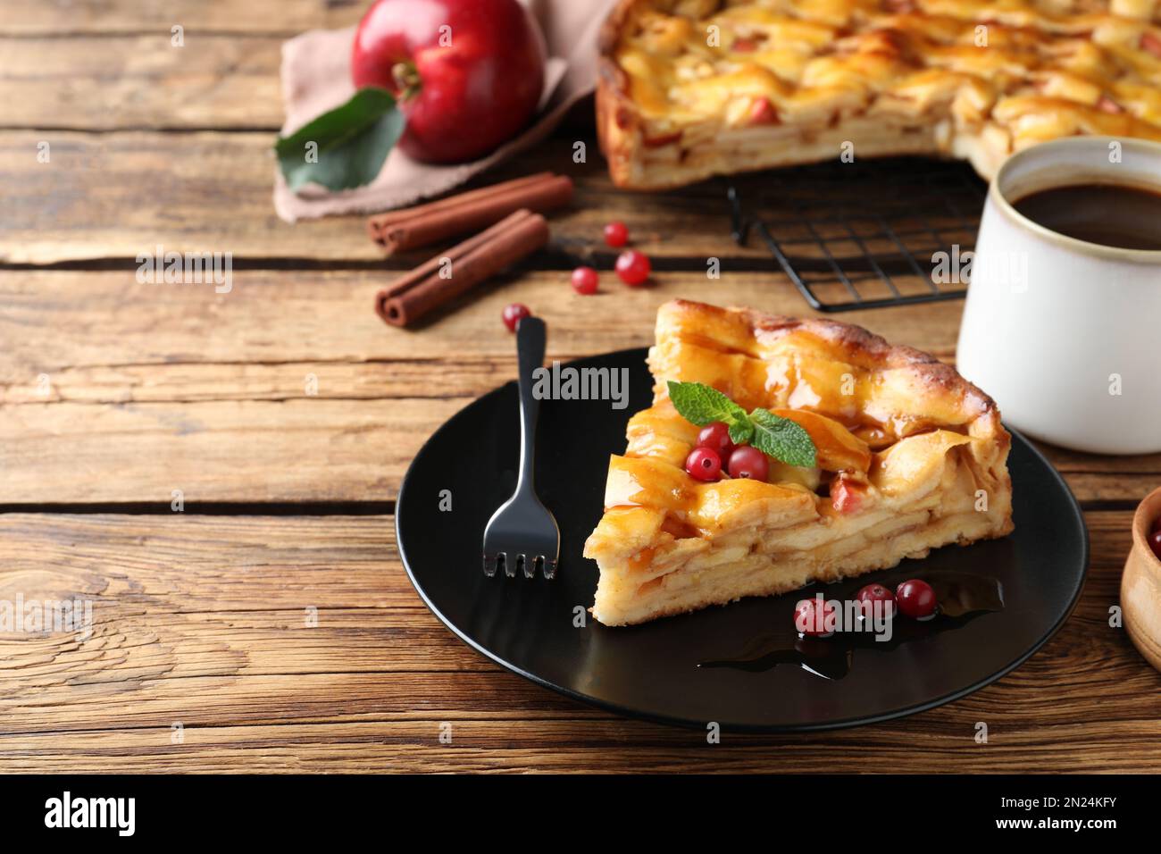 Slice of traditional apple pie with berries served on wooden table Stock Photo