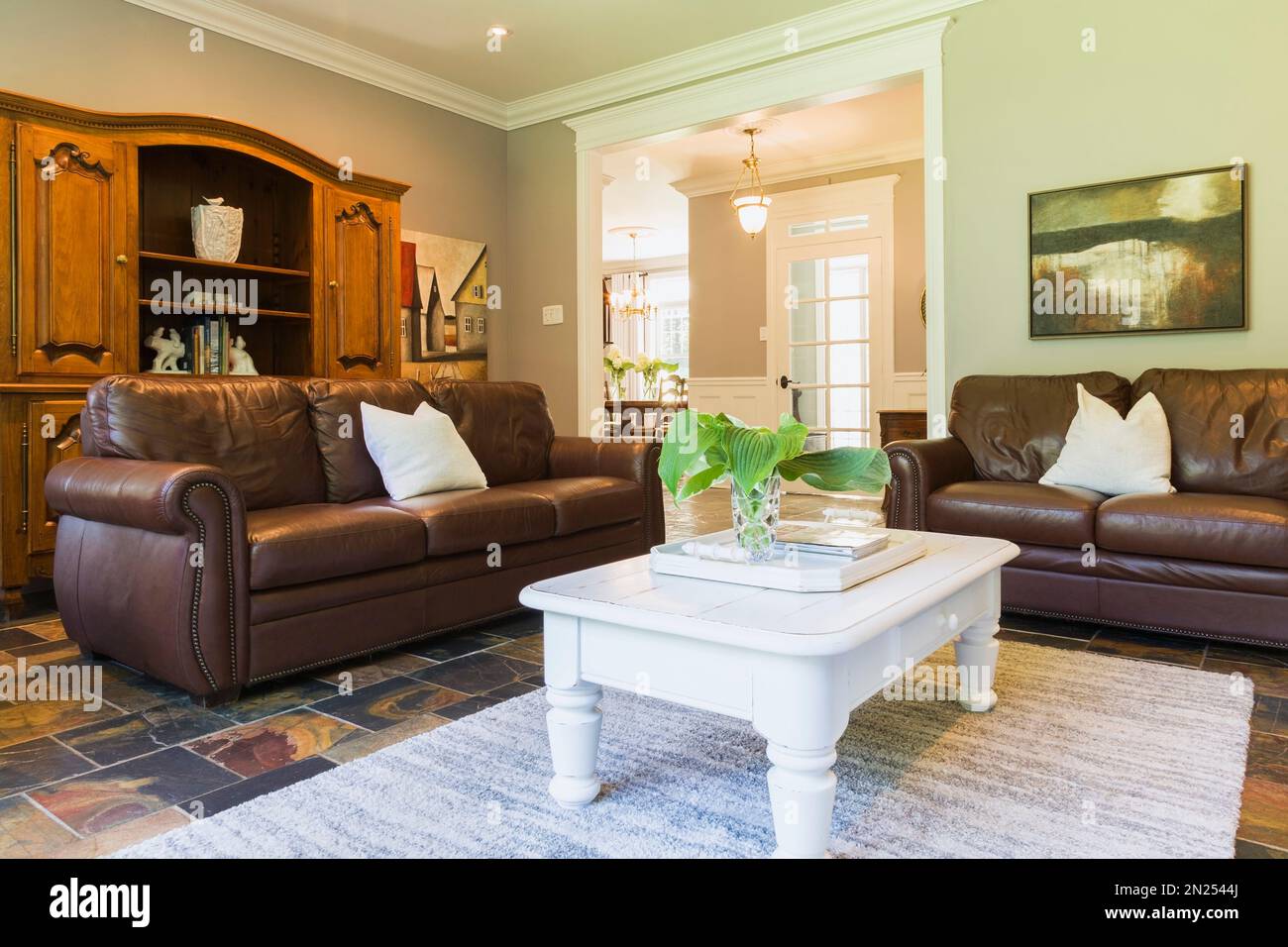 White wooden coffee table with brown leather sofas and wooden buffet in living room with earth