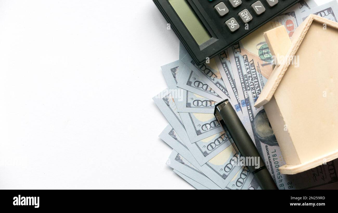 Note Business Money A calculator, pen and house model on a dollar money or bank notes on ...